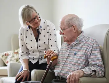 an old lady is taking care of her husband who is suffering from dementia