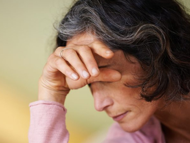 an old caregiving lady seems stressed and burnout having one of her hand forehead